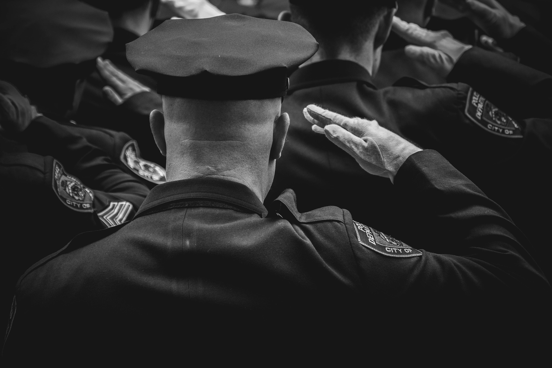 behind view of police officer saluting in a line of police offers