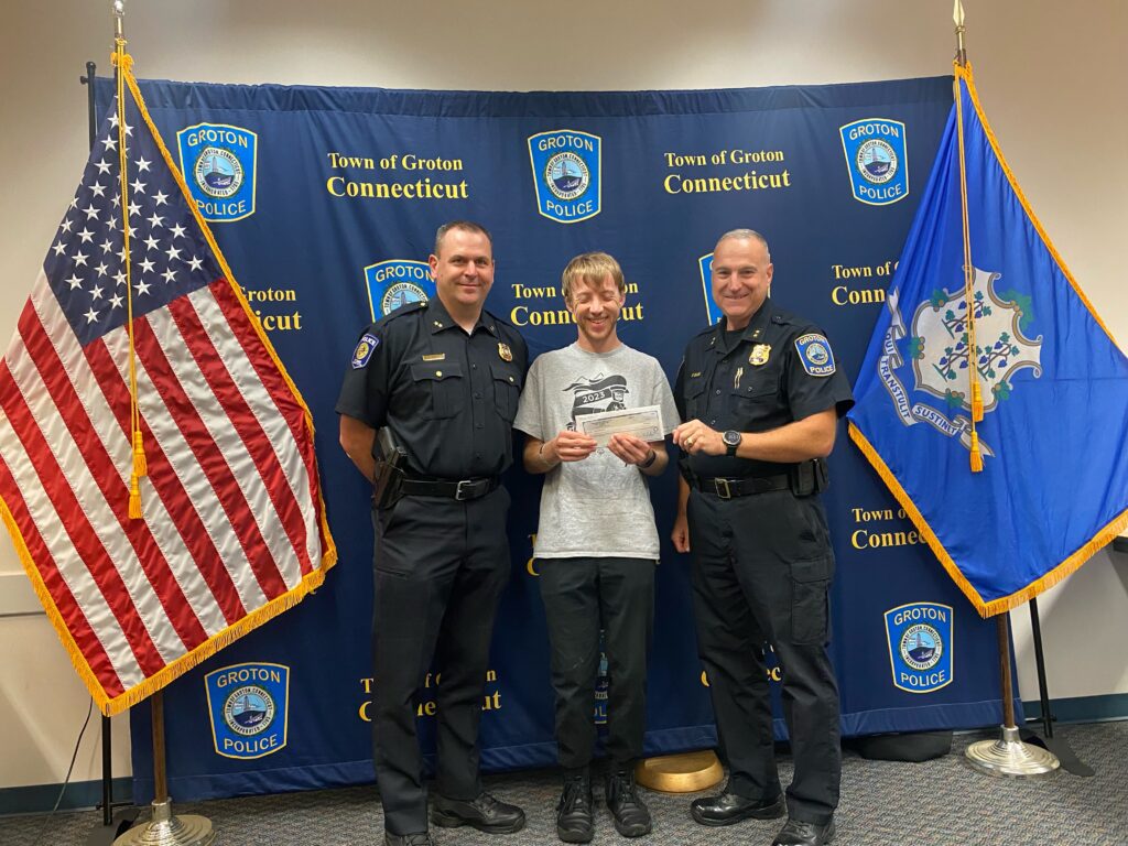 two police officers presenting a check to a young man
