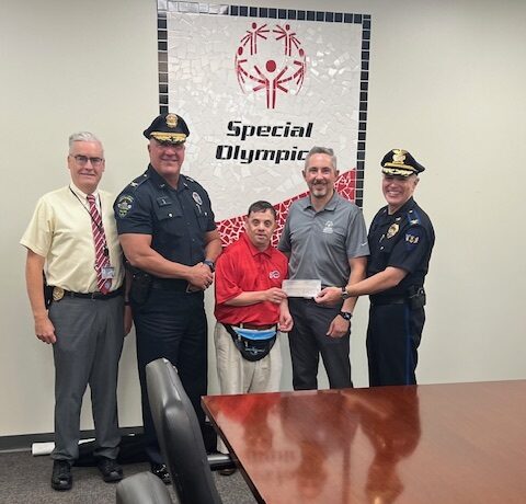 Police officers presenting a donation check to special Olympics representatives