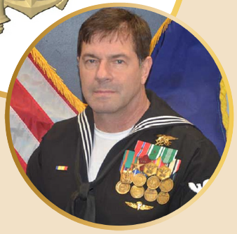 2025.NEACOP-DragoSnip man in navy uniform decorated with medals in front of an American flag