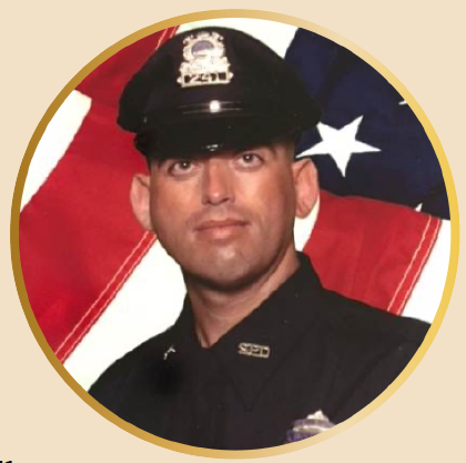 2025.NEACOP.OlivieraSnipCircle man in policing uniform and hat in front of an american flag