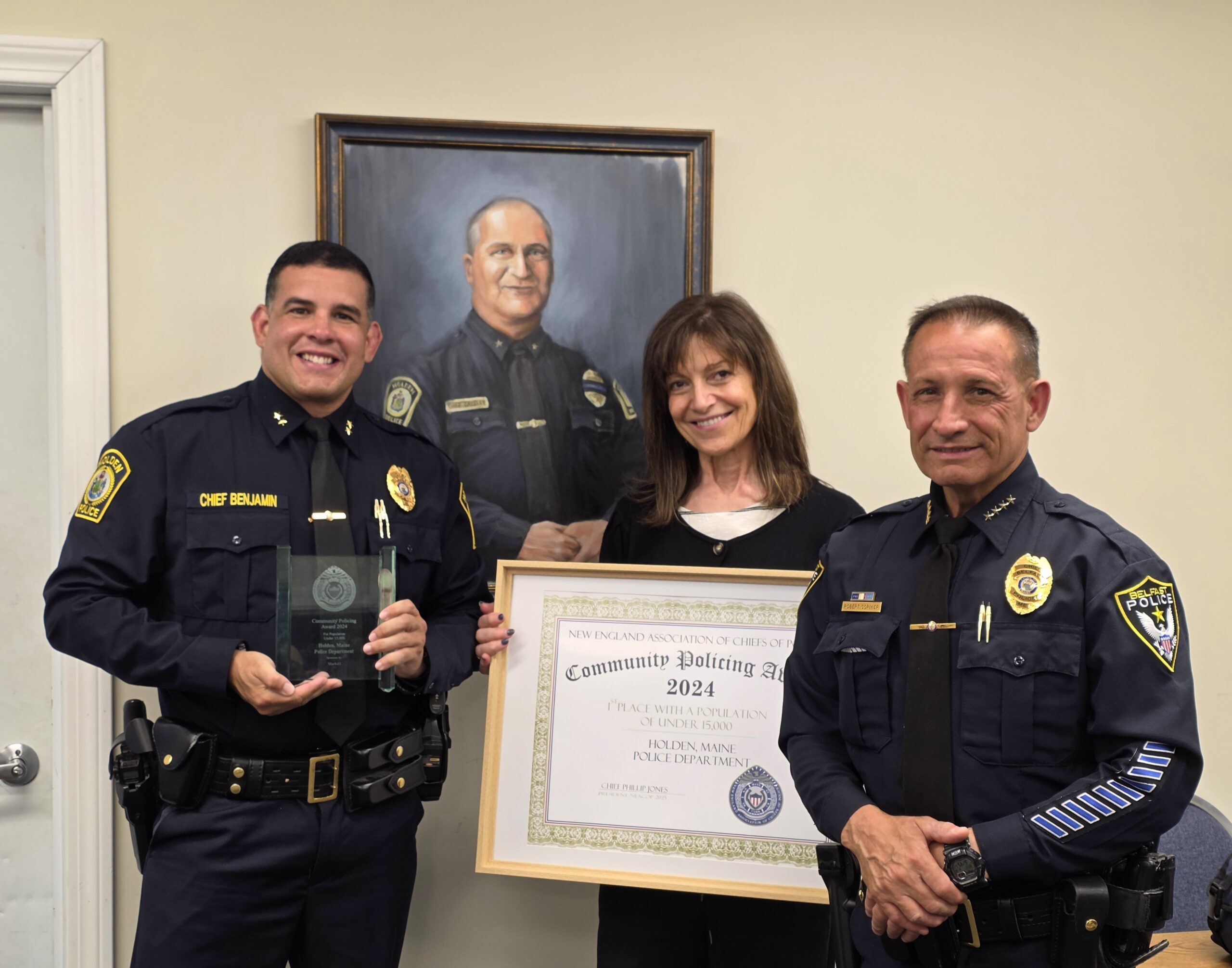 an award presented to two police officers and the chief's wife in front of a police chief painting